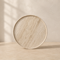 The Cornice, a beige travertine plate by Lomāe, twenty-eight centimetres across with open-pore finish