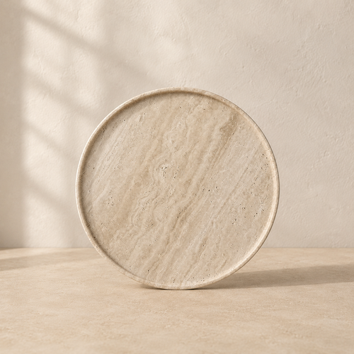 The Cornice, a beige travertine plate by Lomāe, twenty-eight centimetres across with open-pore finish